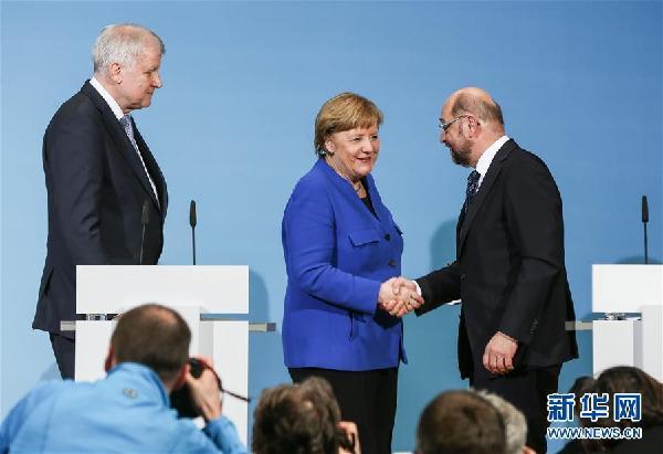 1月12日，在德国首都柏林的社民党总部，德国总理、基民盟主席默克尔（中）和社民党主席舒尔茨（右）在新闻发布会后握手。.j